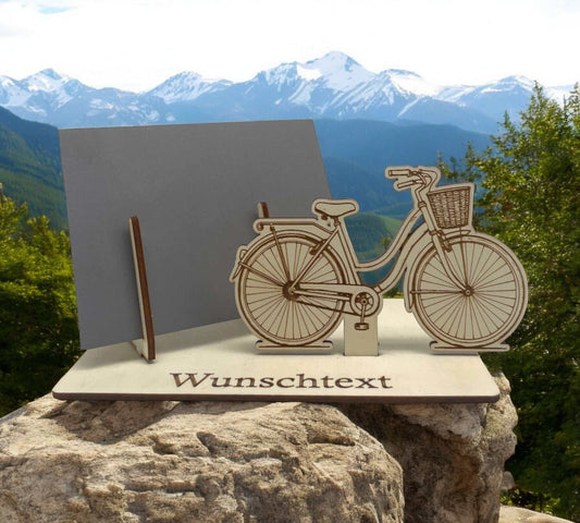 Gutschein verpacken mit graviertem Damenfahrrad mit Korb auf Holzplatte