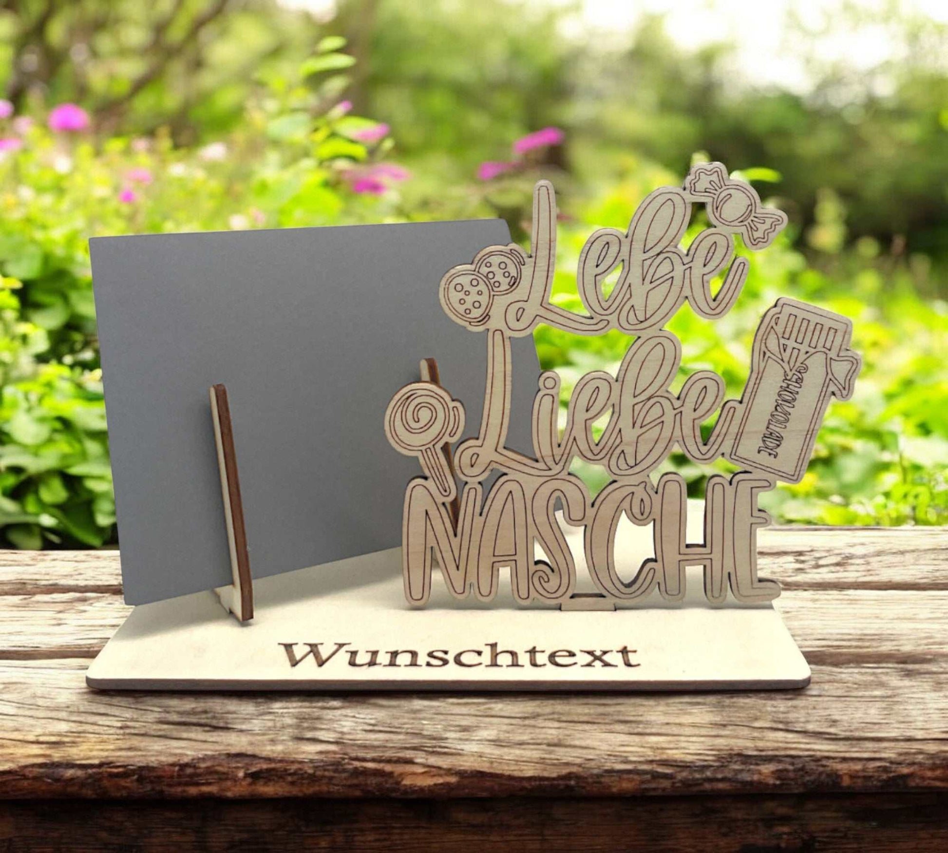 Gutschein verpacken mit Gravur „Lebe Liebe Nasche“ und Süßigkeiten auf Holzplatte