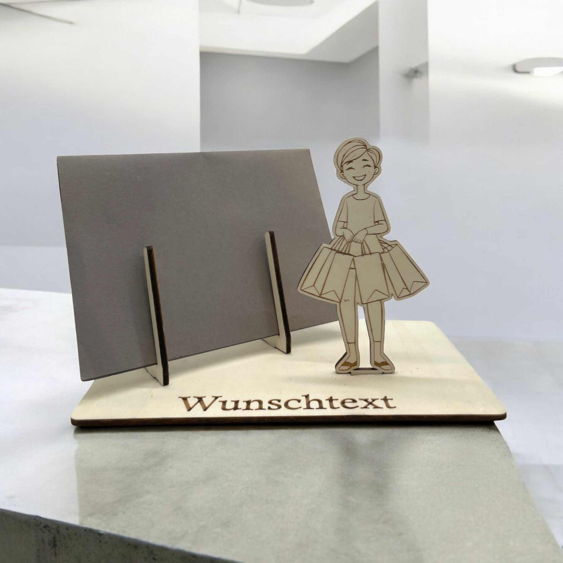 Gutschein verpacken mit Shopping-Motiv – Holzfigur mit Einkaufstaschen und Wunschtext